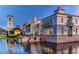 Waterfront buildings with stone accents, multiple levels, and lush landscaping reflected on the water's surface at 789 Cielo Trl, Kissimmee, FL 34759