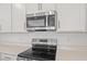 Close-up of kitchen appliances, featuring a stainless steel microwave, oven, and cooktop at 1654 Sugarbelle Cir, Mascotte, FL 34753