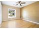 Cozy bedroom with light hardwood floors, neutral paint, and a large sunny window at 7938 Riffle Ln, Orlando, FL 32818