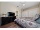 A well-lit bedroom with a ceiling fan, a dresser with TV, hardwood floors, and access to a bathroom at 9509 Baycliff Ct, Orlando, FL 32836