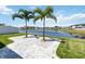 Lush backyard with a picturesque view of the lake, decorative palm trees, and a lovely stone paver patio at 1180 Lone Palm Way, St Cloud, FL 34771