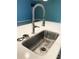 Close-up of a stainless steel kitchen sink with a modern faucet and white countertop at 1180 Lone Palm Way, St Cloud, FL 34771