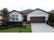 Charming one-story home featuring a well-manicured lawn, a two-car garage, and stylish architectural details at 1271 Yorkshire Ct, Davenport, FL 33896