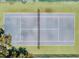 Aerial view of a tennis court with a net and surrounded by trees and fencing at 2804 Club Cortile Cir # A, Kissimmee, FL 34746