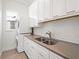 Bright laundry room featuring stacked washer and dryer, white cabinetry, and stainless steel sink at 8352 Lookout Pointe Dr, Windermere, FL 34786