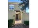 Close up of a 2 story tan stucco townhome with arched windows, red tile entry roof and brick walkway at 2550 Bella Vista Dr, Davenport, FL 33897