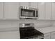 Close up of modern stainless steel microwave and stovetop with white countertops at 317 Alexandrite St, Deland, FL 32720