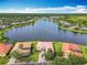 Beautiful aerial view of a lakefront home with lush green lawn, terracotta roof, and access to community amenities at 644 Shorehaven Dr, Kissimmee, FL 34759
