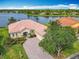 Waterfront home featuring lush landscaping, a brick paver driveway, and terra cotta roof, backing onto a tranquil lake at 644 Shorehaven Dr, Kissimmee, FL 34759