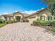 Paver driveway leading to a well-maintained home with a two-car garage and lush landscaping at 644 Shorehaven Dr, Kissimmee, FL 34759