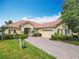 Charming home featuring a brick driveway, terra cotta roof, manicured landscaping, and an attached two-car garage at 644 Shorehaven Dr, Kissimmee, FL 34759