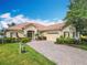 Charming home featuring a brick paver driveway, terra cotta roof, manicured landscaping, and attached two-car garage at 644 Shorehaven Dr, Kissimmee, FL 34759