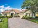 Charming home featuring brick paver driveway, terracotta roof, manicured landscaping, and an attached two-car garage at 644 Shorehaven Dr, Kissimmee, FL 34759
