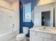 Bathroom with a tub, shower, toilet, vanity and white cabinets with a blue accent wall at 1326 Butterfly Orchid Rd, Davenport, FL 33837