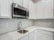 Close-up of a stainless steel sink, faucet, and white cabinets with quartz countertops at 1326 Butterfly Orchid Rd, Davenport, FL 33837