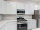 Close-up of modern gas range with stainless steel microwave, white cabinets, and quartz countertops at 1326 Butterfly Orchid Rd, Davenport, FL 33837