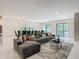 Open-concept living and dining area features a large gray sofa and backyard access at 1326 Butterfly Orchid Rd, Davenport, FL 33837