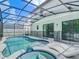 This backyard features a screened-in pool, spa, and lounge chairs at 1326 Butterfly Orchid Rd, Davenport, FL 33837