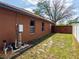 Side yard view with exterior utilities, white fence, and dark wood fence and greenery at 20249 Macon Pkwy, Orlando, FL 32833