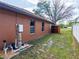 Side yard view with exterior utilities, white fence, and dark wood fence on a bright day at 20249 Macon Pkwy, Orlando, FL 32833