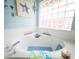 Close-up of a luxurious soaking tub with bright natural light from a glass block window at 20249 Macon Pkwy, Orlando, FL 32833