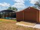 View of the backyard shed and screened in pool area with clear blue water on a bright day at 20249 Macon Pkwy, Orlando, FL 32833