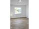 Bright bedroom featuring wood-look flooring and a window showcasing lush greenery at 2227 Coventry Dr, Winter Park, FL 32792