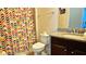 Bright bathroom featuring a granite vanity, a sink and a toilet next to the shower/tub with a colorful curtain at 228 Captiva Dr, Davenport, FL 33896