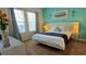 Bright bedroom featuring a queen-sized bed with a white comforter and teal accent wall, illuminated by natural light at 228 Captiva Dr, Davenport, FL 33896