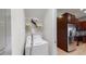 Efficient laundry area with a white washing machine, wire shelving and adjoining kitchen boasting dark cabinetry and stainless steel appliances at 228 Captiva Dr, Davenport, FL 33896