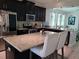 Modern kitchen featuring dark cabinets, stainless steel appliances, granite countertops, and a center island with bar seating at 2522 Nouveau Way, Kissimmee, FL 34741