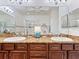 Bathroom featuring double sinks with granite countertops, large mirrors, and a glass-enclosed shower at 2724 Palm Tree Dr, Poinciana, FL 34759