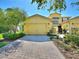 Charming yellow home features a two-car garage and a beautifully paved driveway at 2724 Palm Tree Dr, Poinciana, FL 34759
