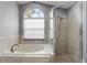Bright bathroom with a soaking tub, shower, and a large window providing natural light at 3111 Turnberry Blvd, Kissimmee, FL 34744