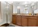 Well-lit bathroom featuring double sink vanity with wood cabinetry, a framed mirror, and a glass-enclosed shower at 3610 Rodrick Cir, Orlando, FL 32824