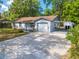 Single-story home with a long driveway, attached garage, and covered parking area, surrounded by mature trees at 412 Noya Ln, Apopka, FL 32712