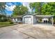 Single-story home with a long driveway, attached garage, and covered parking area, surrounded by mature trees at 412 Noya Ln, Apopka, FL 32712