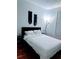 Comfortable bedroom features a bed with white linens, macrame decorations, and a dark wood floor at 6141 Metrowest Blvd # 303, Orlando, FL 32835
