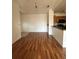 Open-concept living room with hardwood floors flowing into the kitchen and entry area at 6141 Metrowest Blvd # 303, Orlando, FL 32835