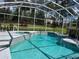 Inviting screened-in pool featuring sparkling blue water and relaxing spa, surrounded by lush landscaping at 618 N Hampton Dr, Davenport, FL 33897