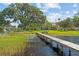 Backyard featuring a large tree, lush grass, and a long wooden dock leading out onto the serene lake at 6200 Alligator Lake E Shr, St Cloud, FL 34771