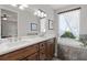 Bathroom features a dual sink vanity with dark wood cabinets, stone countertops, a soaking tub, and a window at 6200 Alligator Lake E Shr, St Cloud, FL 34771