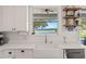 Close up of kitchen with farmhouse sink under window with view of the lake, white backsplash and open shelves at 6200 Alligator Lake E Shr, St Cloud, FL 34771