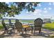 Scenic waterfront view with Adirondack chairs around a firepit, leading to a dock and boathouse on a sunny day at 6200 Alligator Lake E Shr, St Cloud, FL 34771