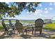 Scenic waterfront view with Adirondack chairs around a firepit, leading to a dock and boathouse on a sunny day at 6200 Alligator Lake E Shr, St Cloud, FL 34771