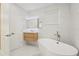 Bright bathroom featuring a freestanding tub, modern vanity, and elegant white marble-style tile at 6632 Pasturelands Pl, Winter Garden, FL 34787