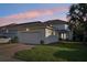 Inviting exterior of a home with a well-manicured lawn, garage, and a colorful sunset in the background at 6632 Pasturelands Pl, Winter Garden, FL 34787