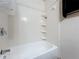 Clean, tiled bathtub and shower area featuring built-in storage shelves at 690 W Pearl St, Bartow, FL 33830