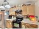 A kitchen featuring a stainless steel refrigerator, black stovetop, and wood cabinets and mosaic tile backsplash at 690 W Pearl St, Bartow, FL 33830