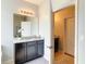 Bathroom featuring a vanity with granite countertop, decorative mirror, and view into another room at 8039 Oak Shadow Ct, Davenport, FL 33837